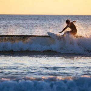 Surfer surfeando una ola en clase de surf al atardecer