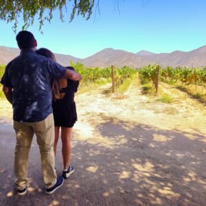 Pareja paseando entre viñedos y cerros bajo el sol